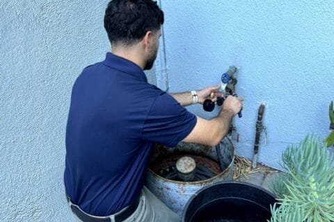 Man on outside of house tightening hose with wrench