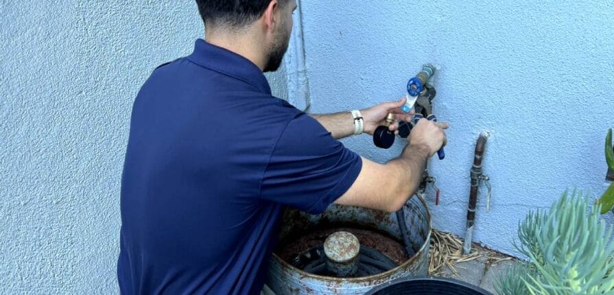 Man on outside of house tightening hose with wrench