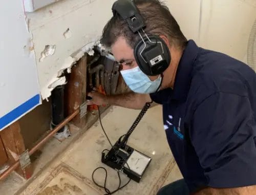 Man detecting water leak with tool